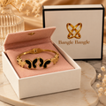 18K gold plated black butterfly cuff bangle in open Bangle Bangle white gift box with black trim and pink pouch on marble surface — Bangle Bangle