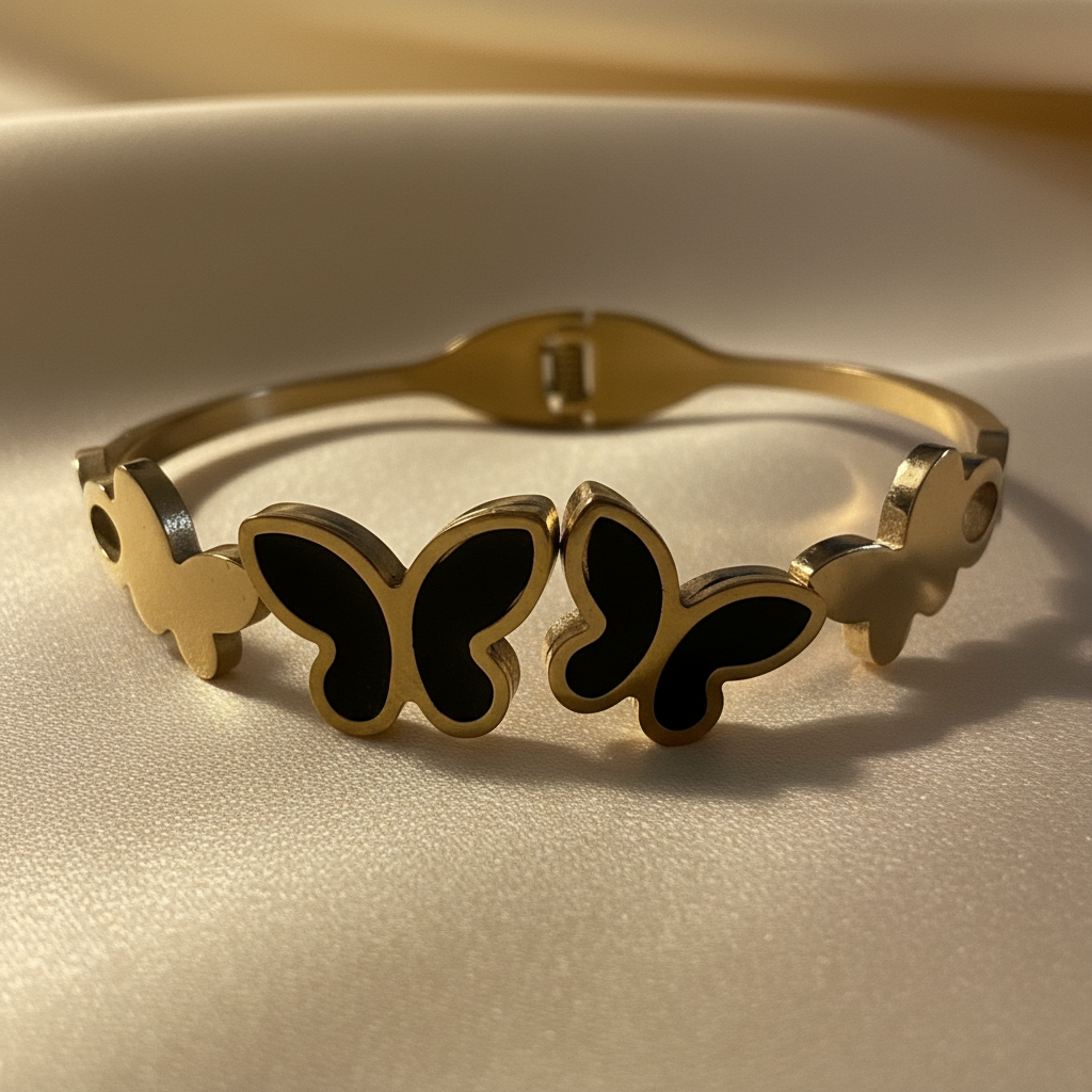 Close-up of 18K gold plated black butterfly cuff bangle showing black enamel butterfly motifs and polished gold frame detailing on cream satin — Bangle Bangle