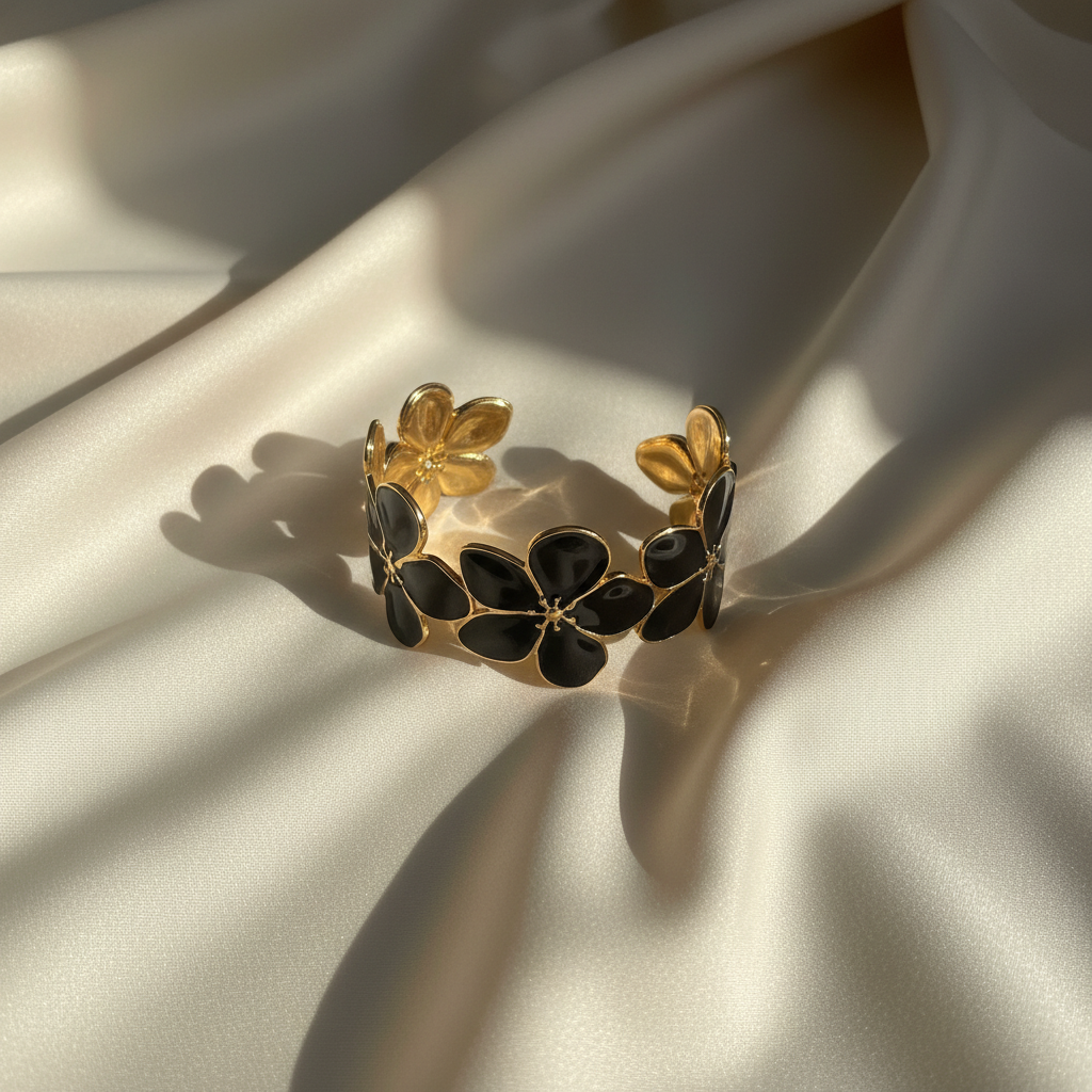 18K gold plated black floral blossom cuff bangle with black enamel petals laid flat on cream satin fabric — Bangle Bangle