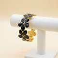 18K gold plated black floral blossom cuff bangle with black enamel petals displayed on a jewellery stand — Bangle Bangle