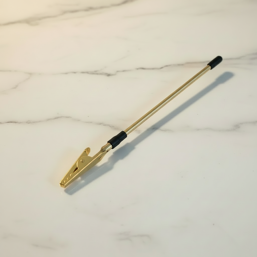 Gold bracelet helper tool with alligator clip and rubber tip on a white marble surface — Bangle Bangle