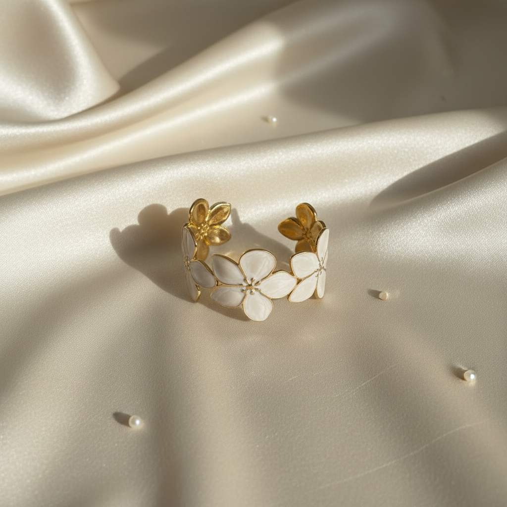 18K gold plated floral blossom cuff bangle with white enamel flowers laid flat on cream satin fabric — Bangle Bangle